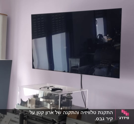 טלוויזיה מותקנת על קיר עם רמקולים ומערכת סטריאו